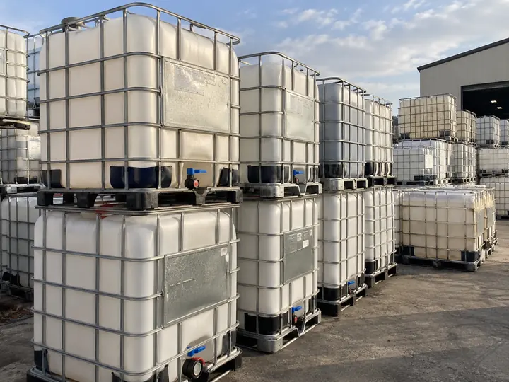 Caged totes stacked two high with their data plates facing the camera.